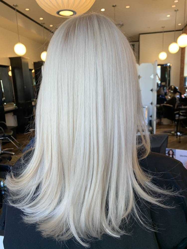 Sleek, straight platinum blonde hair in a modern salon setting.